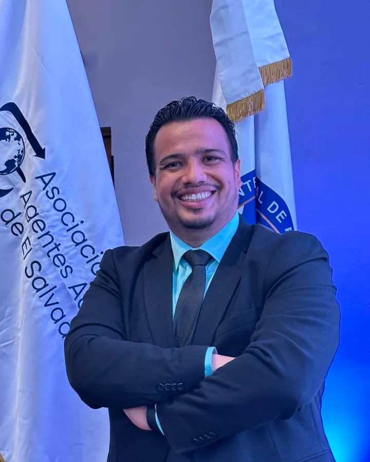 Marco Antonio Cruz Hernández, agente aduanero de MACH Customs Agency, junto a la bandera de ASODAA